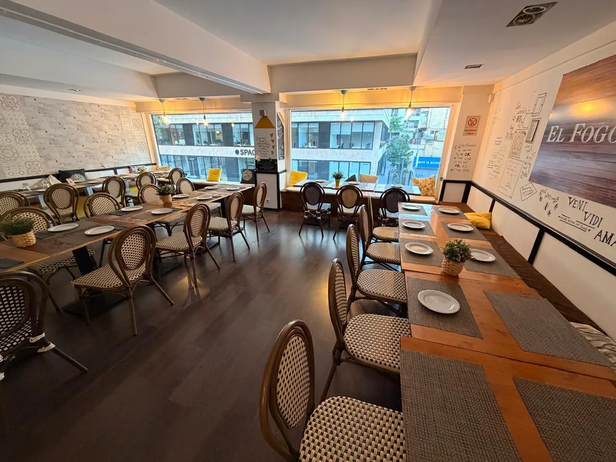 Salón superior preparado para un grupo, con mesas largas y vistas al exterior