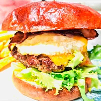 Deliciosa hamburguesa con queso fundido, bacon crujiente y verduras frescas en un pan tostado.